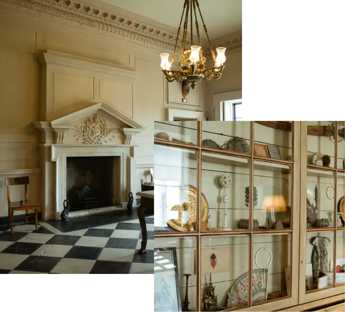 A room with an ornate fireplace, checkered floor, and a vintage chandelier on the ceiling. Adjacent is a display cabinet filled with various antique items and curiosities.